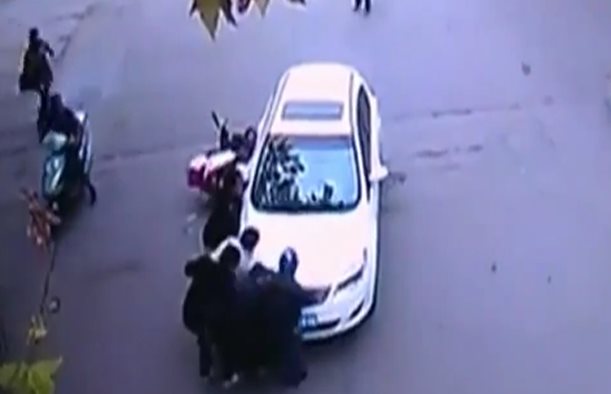 Transeúntes levantan un auto para rescatar a una mujer atropellada