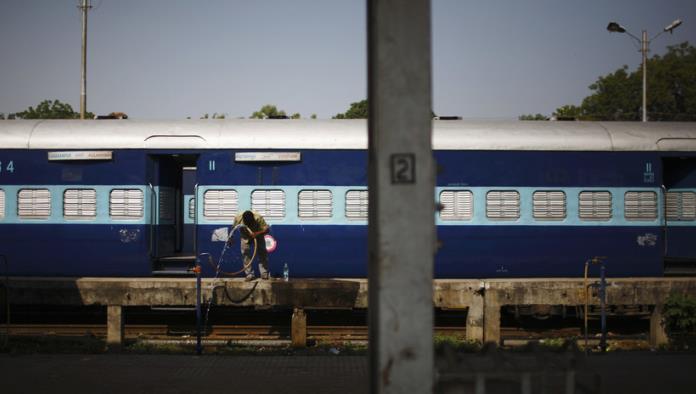 Un tren arrastra a un joven a lo largo de un andén en la India