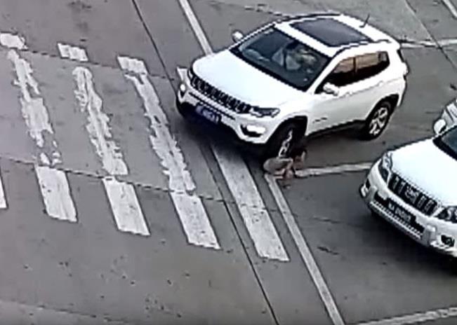 Una niña se agacha para atarse los cordones y un auto le pasa por encima