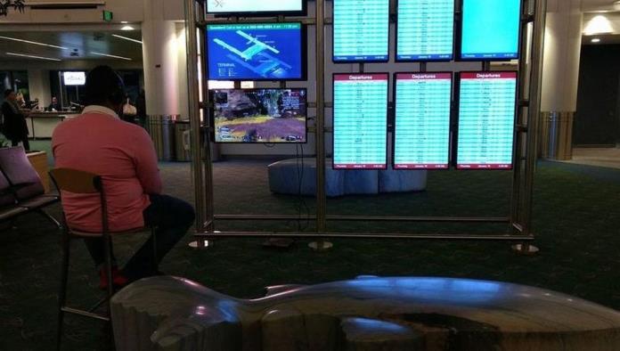 Hombre conecta su consola de videojuegos en pantalla de aeropuerto